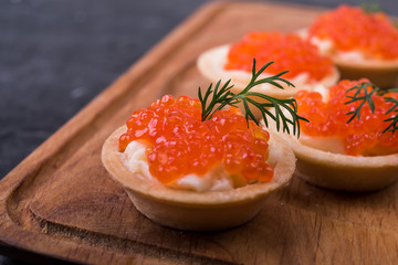 Canapes with salmon red caviar on a black  background