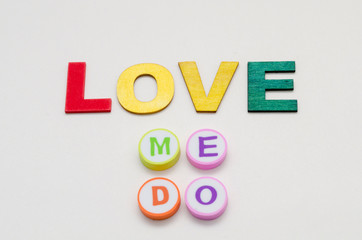 Love me do phrase made from colorful letters made of wood and erasers against white background