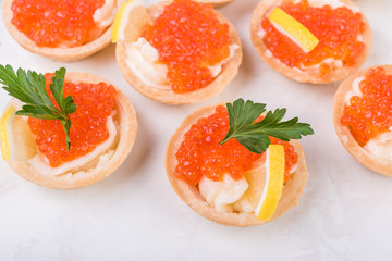 Tartlets with red caviar on white background. Selective focus.
