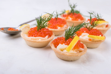 Tartlets with red caviar on white background. Selective focus.