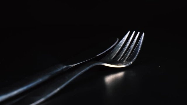 Rotating knife and fork that glitter against black background