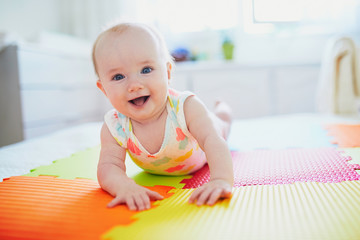 baby girl lying on colorful play mat on the floor