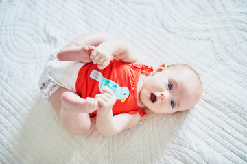 Cute baby girl lying on her back and touching her feet