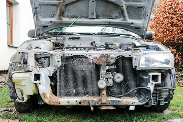 A detail of the old car wreck. The front of the car is visible, some parts are missing. The engine...