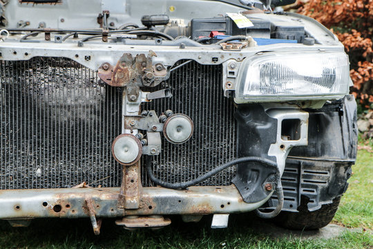 A detail of the old car wreck. The front of the car is visible, some parts are missing. The engine and radiator are without cover. 