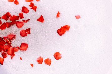 St. Valentine's Day bath. Aromatherapy with flower petals. Take a bath. Water with white foam. Roses float in the bathroom.