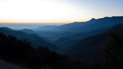 Sun rising on a foggy dark mountain range silhouette in Catalan Pyrenees