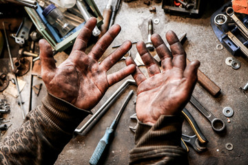 A picture of dirty hands of a guy from the garage. Hard and dirty work is behind him. 