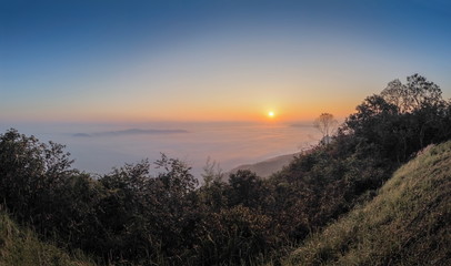 Obraz premium sunrise at Doi Samur Dao, mountain view misty morning of the hill around with sea of mist with colorful of yellow sun light in the sky background, Sri Nan National Park, Nan Province, Thailand.