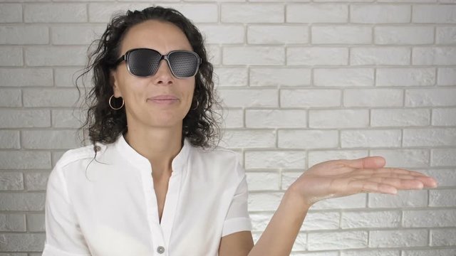 Woman with pinhole glasses. A woman in glasses for training vision shows her hand.