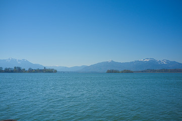 Blick &uuml;ber den Chiemsee in Richtung Alpen mit blauem Himmel und klarer Sicht
