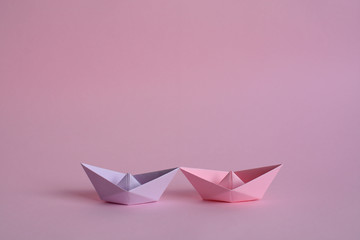 Purple and rose paper boats on pastel pink background. A pair of paper ships that symbolize eternal...