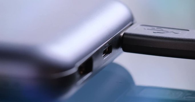 Hand holding USB type C and USB-A cables to connect or disconnect to power bank.