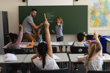 Schoolboy pointing finger towards classmates in classroom
