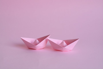 two light pink paper boats on a light pink background. lesbian love.