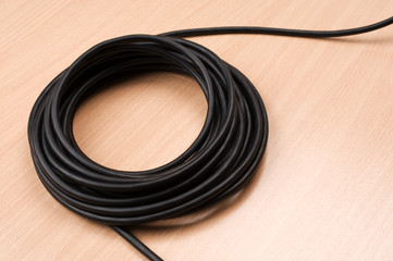 Black electric cable on wooden table.