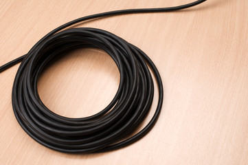 Black electric cable on wooden table.