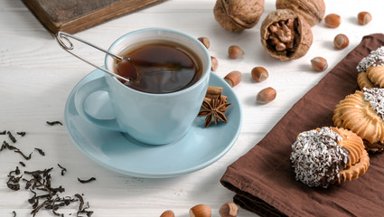 cup of tea with gingerbread and nuts on wooden white background.