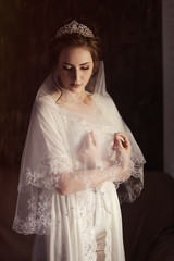 bride in tiara and veil. A girl at a wedding gathering in underwear and a white robe covers herself...