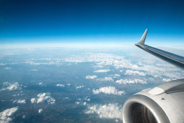A view from the airplane to the ground during the flight. The blue sky is visible and also the clouds. 