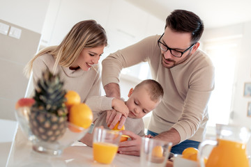 Obraz na płótnie Canvas Happy family make orange juice in morning