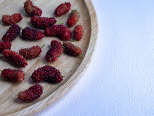 Mulberry fruit mulberry many both purple red orange in the plate made of wood all laid are on a white background.