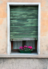 rectangular window with broken blind of an old house with a balc
