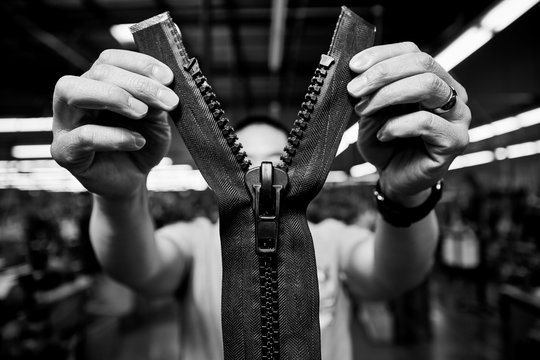 Mans hands holding oversized zipper, black and white