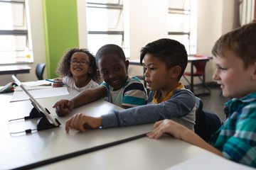 Side view of schoolkids studying on digital tablet while sitting