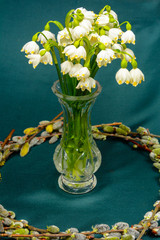 Spring flowers in a crystal vase, a circle of willow branches on a blue background