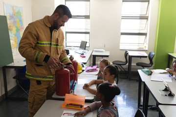 Side view of male Caucasian  firefighter teaching schoolkids