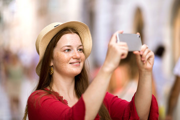Cute girl takes pictures on a smartphone sights in a journey on the streets of Dubrovnik, Croatia. Share your impressions!