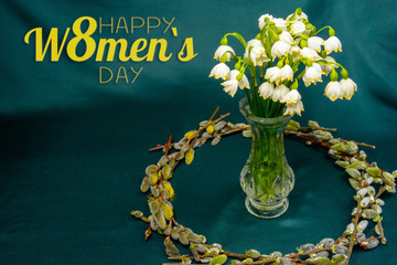 Spring flowers in a crystal vase, a circle of willow branches on a blue background