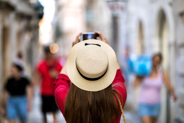 Cute girl takes pictures on a smartphone sights in a journey on the streets of Dubrovnik, Croatia. Share your impressions!