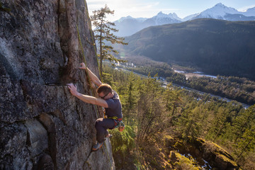 Male Rock climber climbing on the edge of the cliff during a sunny winter sunset. Taken in Area 44...