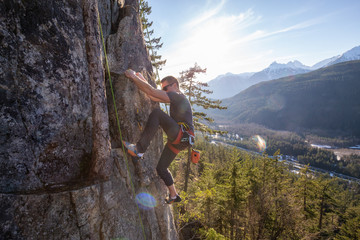 Male Rock climber climbing on the edge of the cliff during a sunny winter sunset. Taken in Area 44...