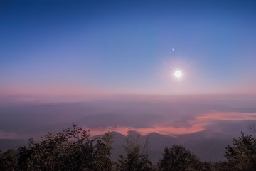 Night photography of moon rising above sea of mist and mountains, Doi Samur Dao, Sri Nan National Park, Nan Province, northern of Thailand.