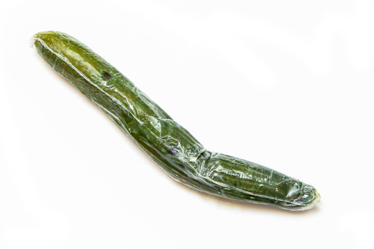 A picture of a rotten cucumber packed in the plastic foil. The foil is useless, it only damages the vegetable and it only goes mouldy. Isolated on a white background.