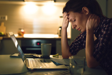 Young woman having a headache while going through home finances