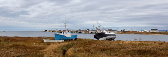 Panoramic view on the small town on the Atlantic Ocean shore with boats parked onshore. Taken in Flower's Cove, Newfoundland and Labrador, Canada.