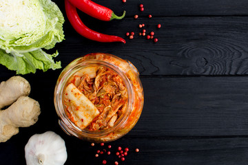 Kimchi in the glass jar and ingredients on the black wooden  background.Top view.Copy space. - obrazy, fototapety, plakaty
