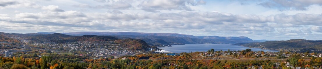 Aerial panoramic view of a modern city on the Atlantic Ocean Coast during a cloudy and sunny day. Taken in Corner Brook, Newfoundland, Canada.