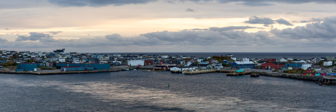 Panoramic view of a little town on the rocky Atlantic Ocean Coast during a cloudy sunset. Taken in Channel-Port aux Basques, Newfoundland, Canada.