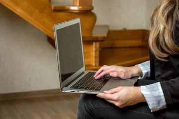 the girl with the laptop sits on a chair to houses