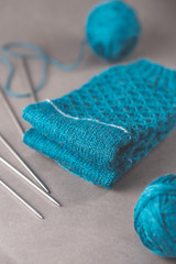 A pair cozy blue socks with two ball of yarn and five stainless steel double pointed needles
