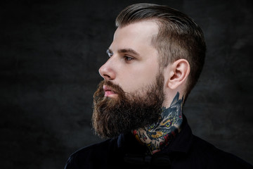 Profile portrait of an expressive bearded man with tattoos on his neck