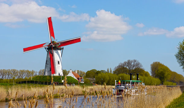 Damme, West Flanders / Belgium - May 2013: A tourist boat crossing the canal between Brugges and Damme, with a windmill in the background