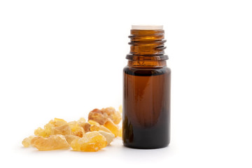 A bottle of frankincense essential oil with frankincense resin on a white background