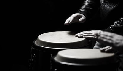 The musician plays the bongo. Close up of musician hand playing bongos drums. Afro-Cuba, rum,...