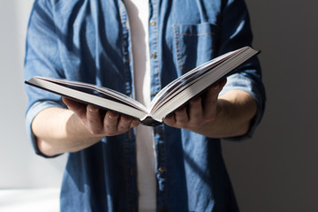 Boy holding book wide open.